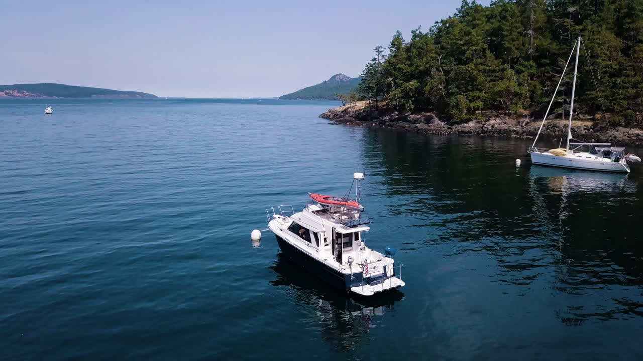 Drone flyover low to water and boats in cove at Jones Island Washington