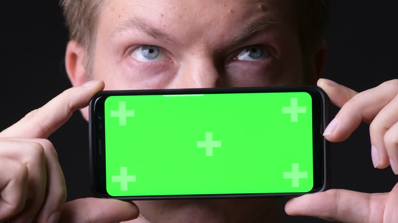 hombre sosteniendo un teléfono móvil con pantalla verde de clave de croma