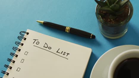 video of notebook with to do list and copy space, coffee and pencil on blue surface