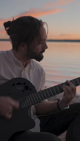 Man Playing Guitar by the Water at Sunset