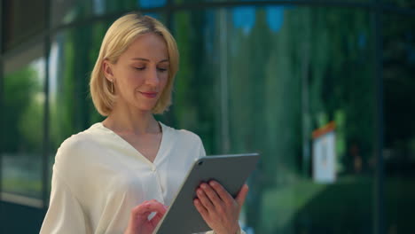 mujer de negocios usando una tableta fuera de un edificio moderno