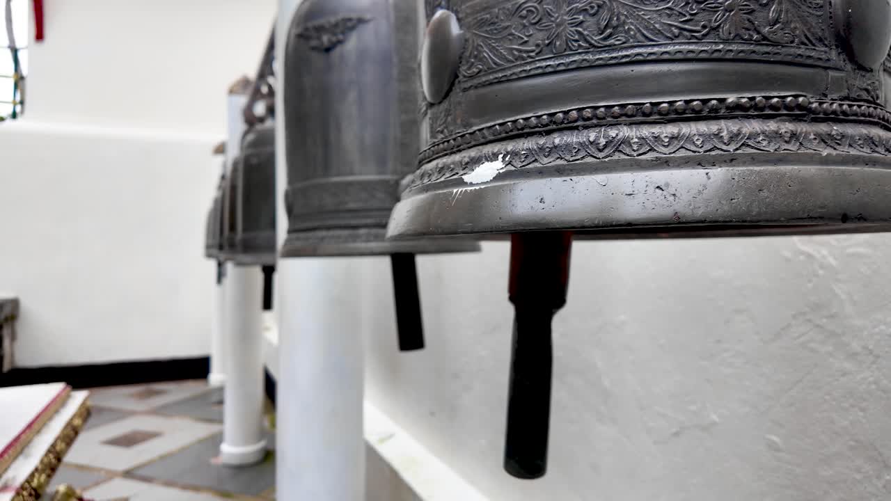 Ornate Buddhist temple bells hanging in a row at a holy site in Chiang Mai