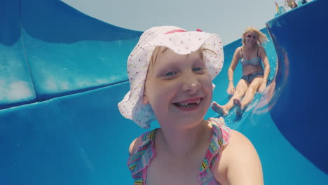 mom and daughter are going fun down the water slide laughing happy family on vacation