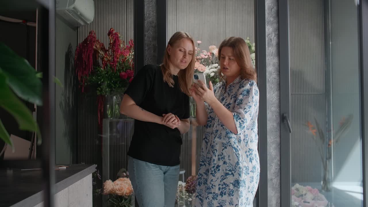 Two women looking at a smartphone in a flower shop