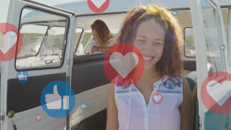 animation of multiple icons over smiling diverse woman standing and man sitting in van at beach