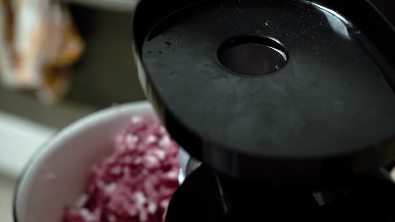 집에서 만든 다진 돼지고기용 고기 분쇄기에 작은 돼지 어깨 조각을 넣습니다.