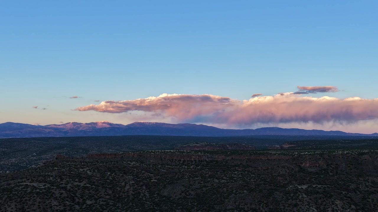 Timelapse 4K con drone cattura raggi radiosi del tramonto e nuvole di pioggia su un versante montuoso scosceso. Il movimento atmosferico cinematografico rivela fasci di luce mutevoli e condizioni meteorologiche tempestose su una vasta distesa desertica.