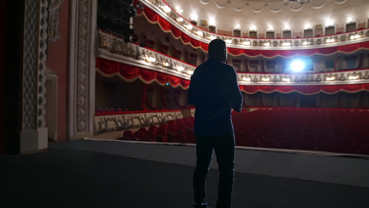 Actor during the rehearsal in large theater. Man performing on stage in front of empty auditorium. Consequences of pandemic.