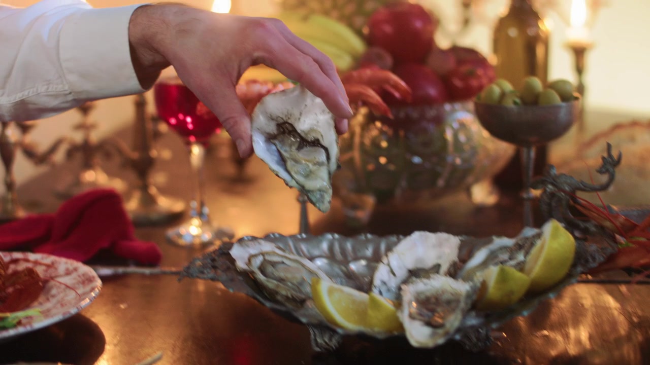 Hand Placing Fresh Oyster on a Plate at an Elegant Dinner Table