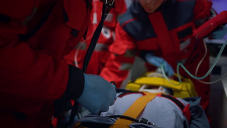 paramedics team examining patient with stethoscope in emergency car