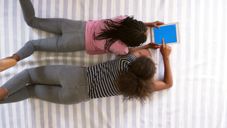 Overhead-View-Of-Teenage-Girls-Looking-At-Digital-Tablet-On-Bed