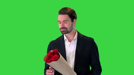 빨간 꽃의 꽃줄을 들고 녹색 스크린, 크로마 키에서 누군가를 기다리는 청년