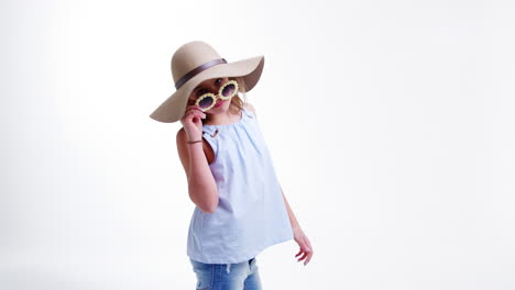 girl wearing hat and sunglasses poses against white background