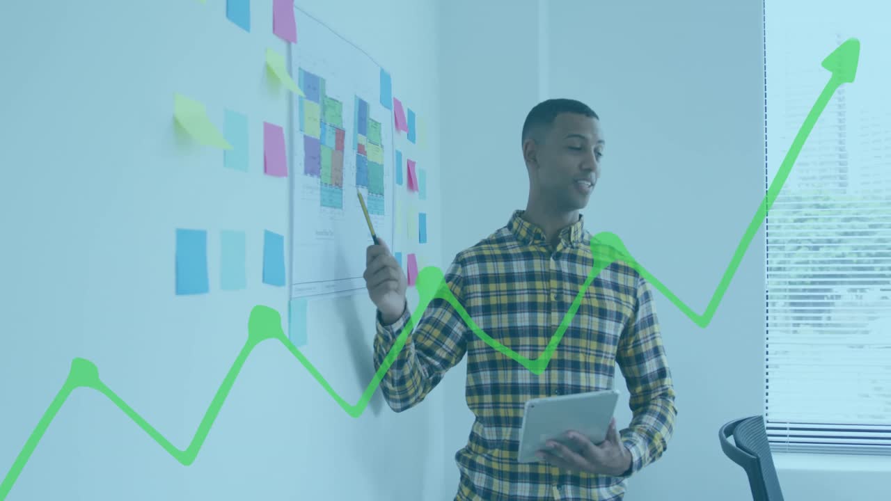 Animation of financial graphs and data over biracial man working in office