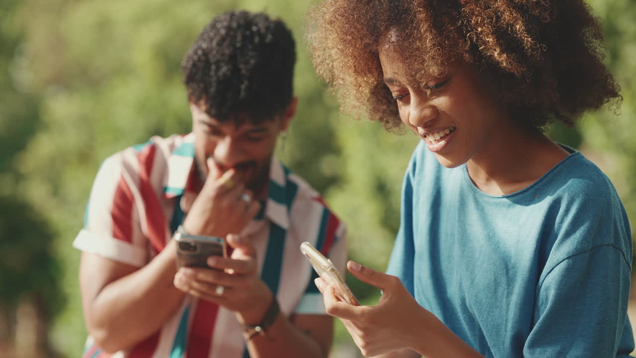 Two people using their phones outside