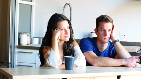 thoughtful couple sitting in kitchen