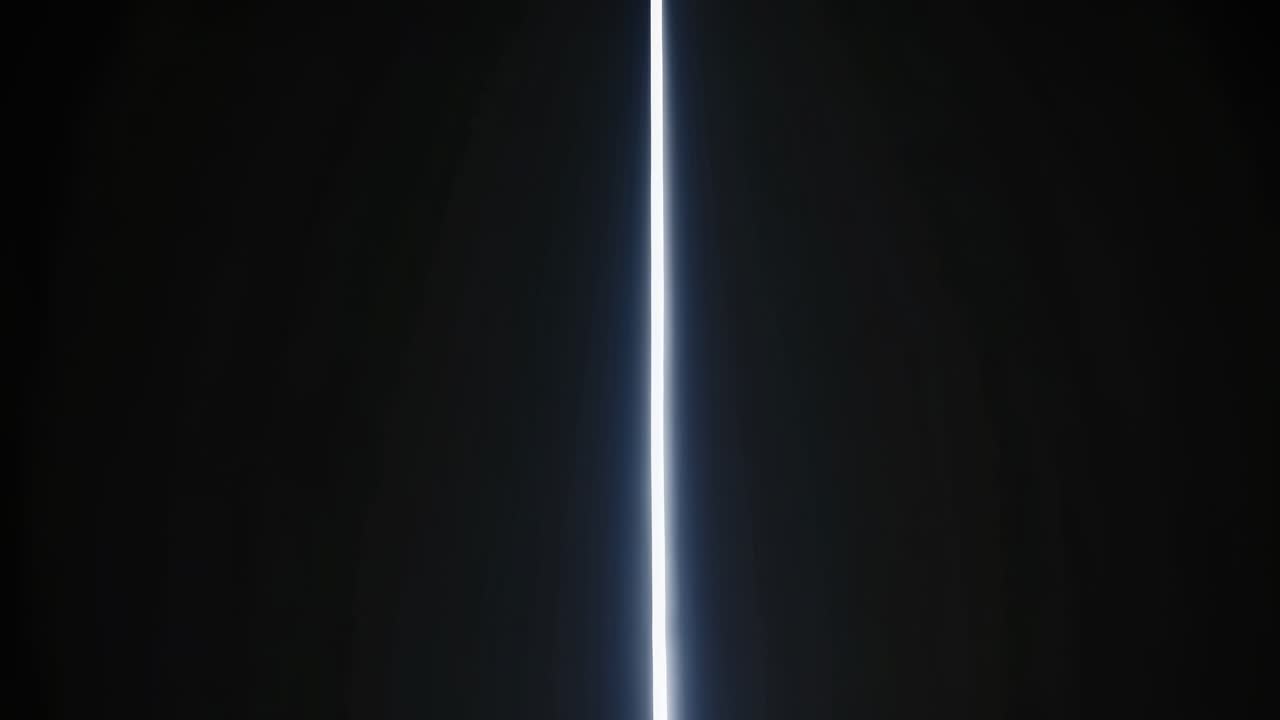 A vertical beam of light pierces through darkness, captured from a low-angle, creating a mysterious