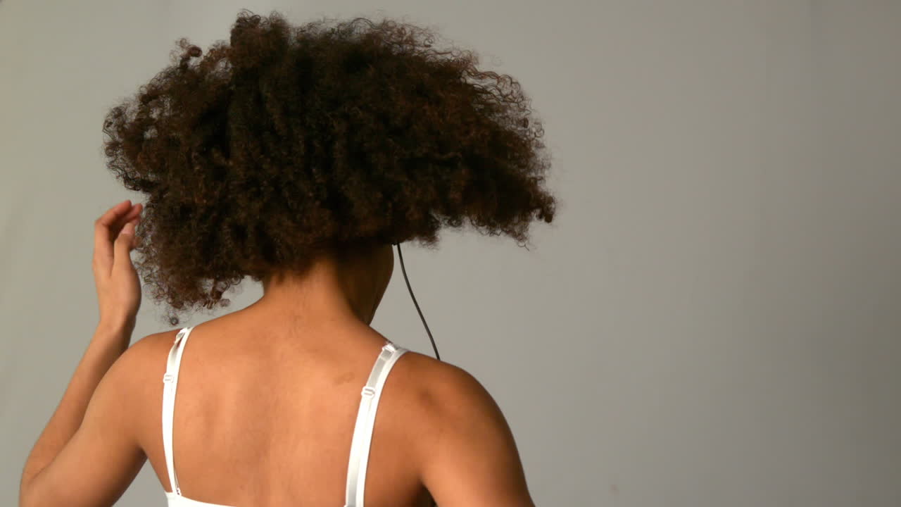 chica bonita con afro saltando y escuchando música