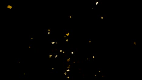 slow motion golden confetti drops from above onto camera lens