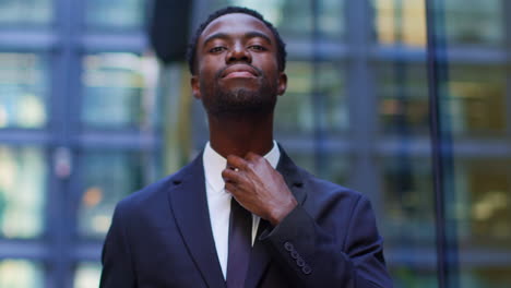 Portrait-Of-Confident-Young-Businessman-Adjusting-Suit-Standing-Outside-Offices-In-The-Financial-District-Of-The-City-Of-London-UK