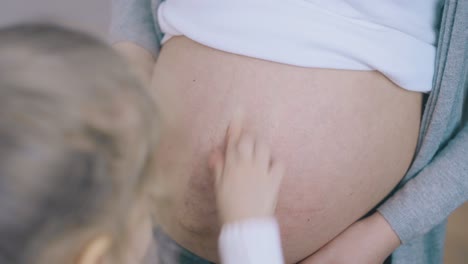 blond girl applies cream on pregnant mommy tummy in room