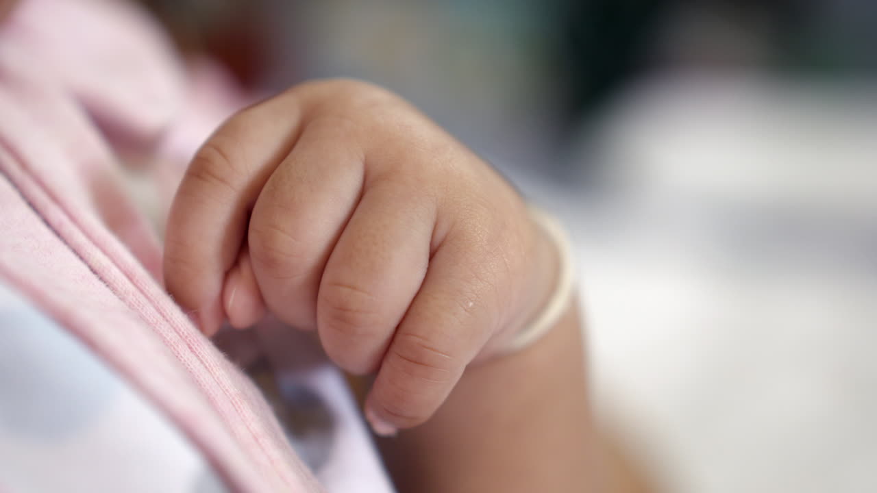 Close-up shot of a newborn baby's tiny hand curled into a knuckle.