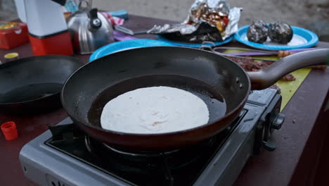 Sprinkling-Cheese-and-Flipping-Quesadilla-on-Outdoor-Grill-and-Skillet-While-Camping