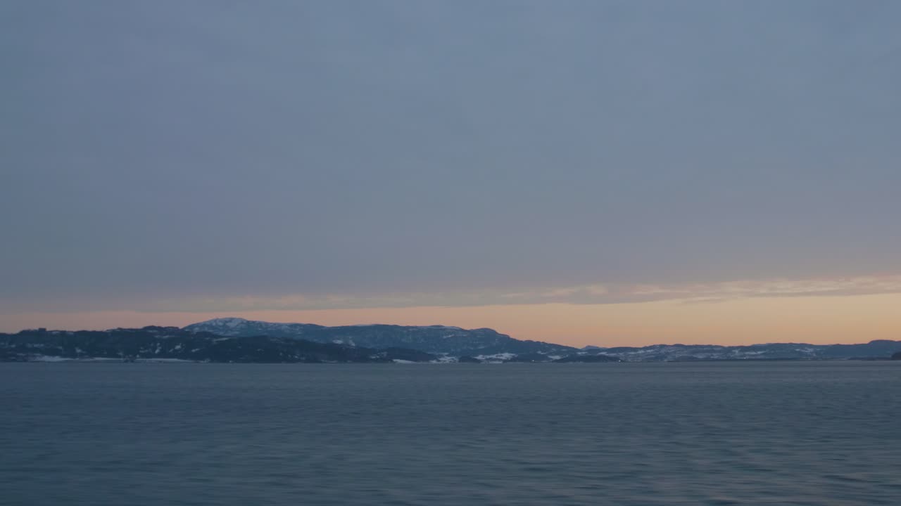 Sunrise over the mountains and a fjord in Norway, that is shot from the moving train