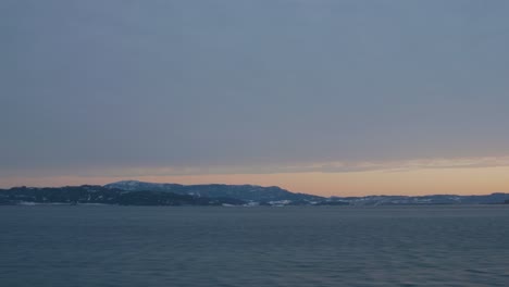 sunrise over the mountains and a fjord in norway, that is shot from the moving train