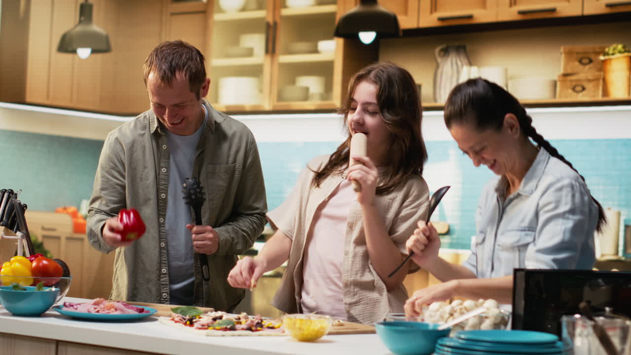 Parents and daughter doing karaoke and dancing together while cooking
