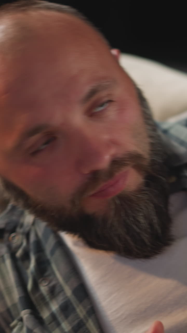 hombre con barba larga se acuesta en el sofá con la mano en el pecho tomando una taza con agua fresca para tragar la píldora. mujer cuida de su marido después de la visita del médico de cerca