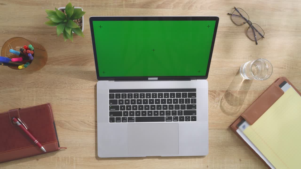 portátil con pantalla verde en un escritorio de madera