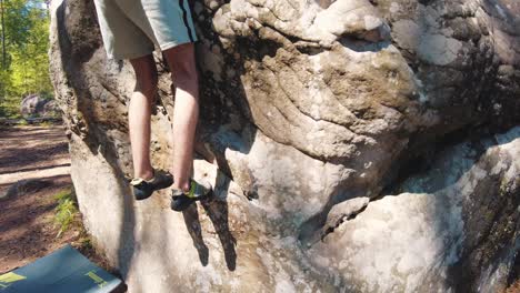 young man's lower half in climbing shoes tiptoeing climb over small edge boulder