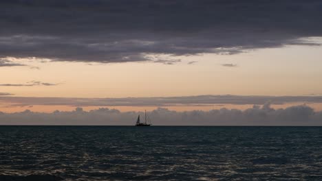 surreal blue hour ocean waves, lone sailing yacht on dark horizon
