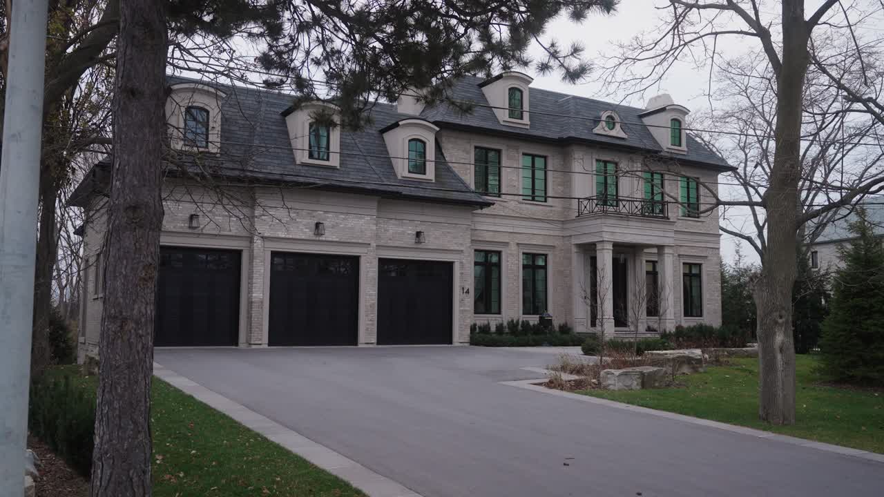 A wide angle establishing shot of a suburban luxury house with spacious driveways, surrounded by greenery and modern design
