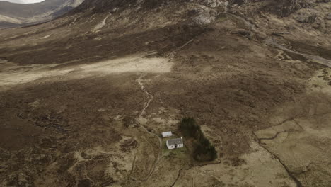 Flying-Over-a-White-Lagangarbh-Hut-in-Glencoe-Scottish-Highlands-with-mountain-Buachaille-Etive-Mor-in-the-distance