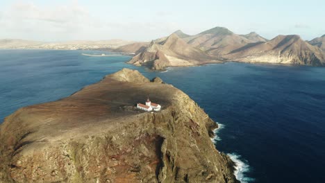 Faro-Remoto-En-Un-Acantilado-Escarpado-De-Una-Isla-Rocosa-Con-Porto-Santo-En-Segundo-Plano