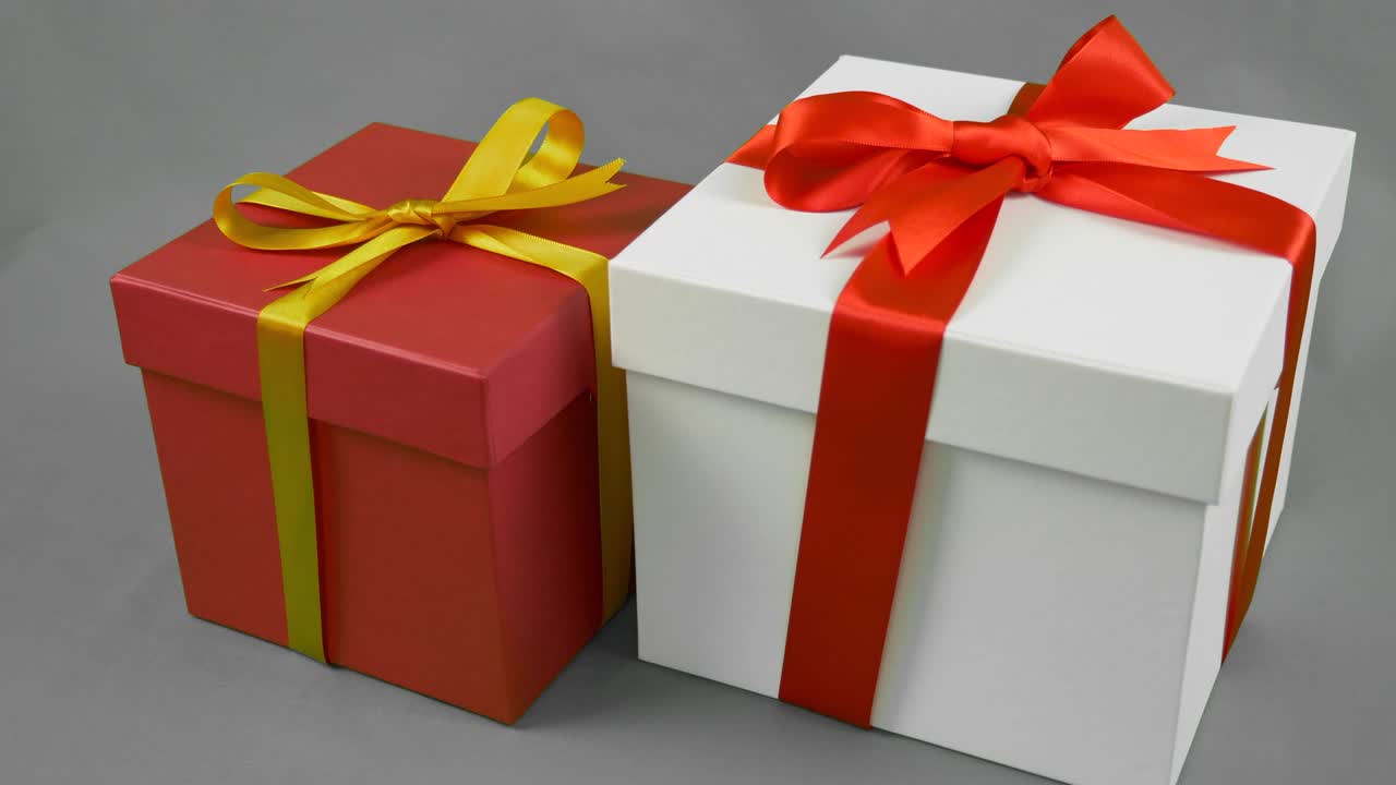 회색 배경의 두 개의 선물 상자, 빨간 리본 활과 은 선물 상자와 금색 노란색 활 스타트.
