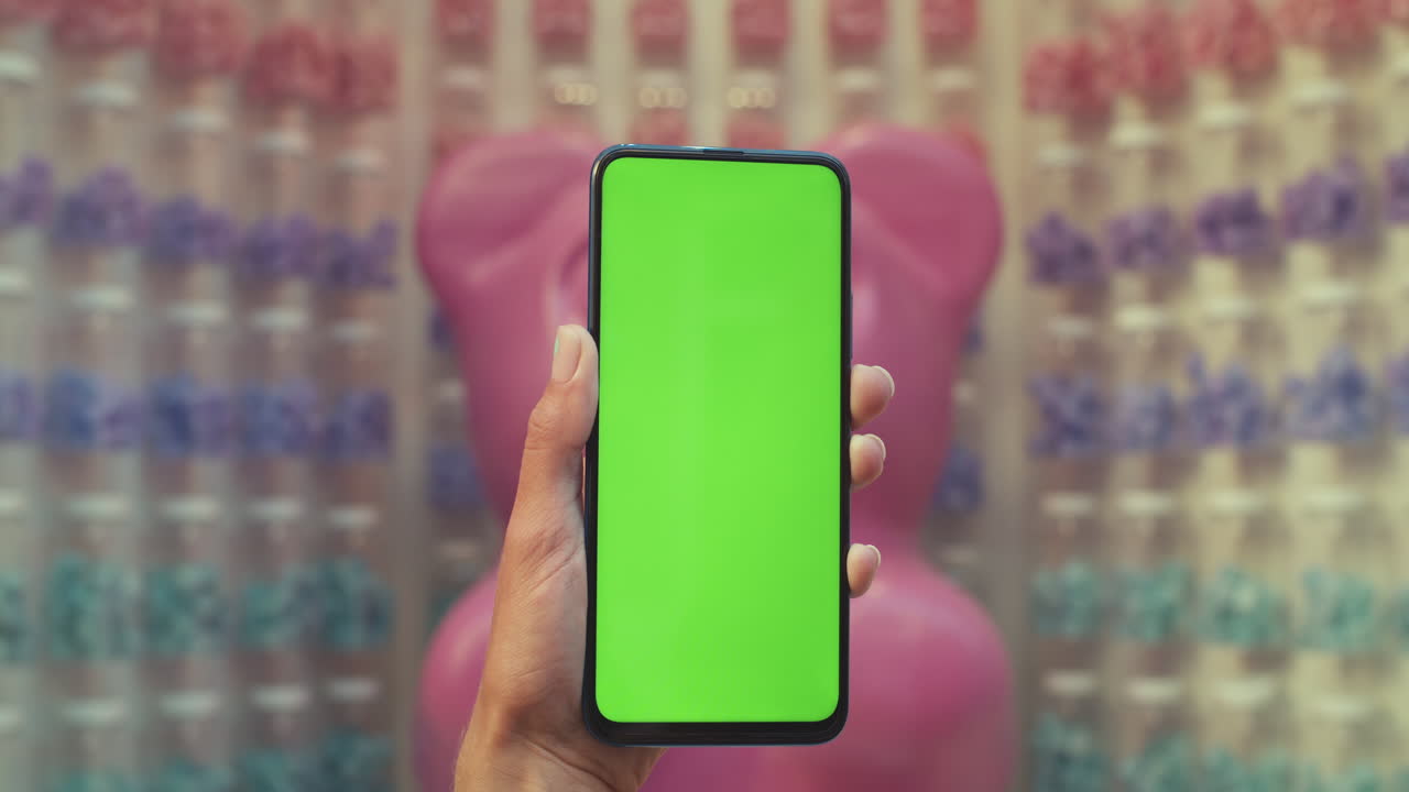Close-up of hands holding a green screen smartphone in a store