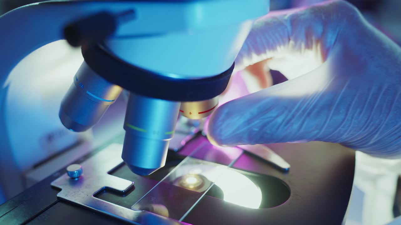 Scientist Adjusting Microscope Lens in a Laboratory