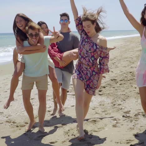 grupo de jóvenes amigos retozando en una playa