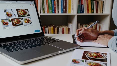 Person Ordering Food Online and Writing Notes