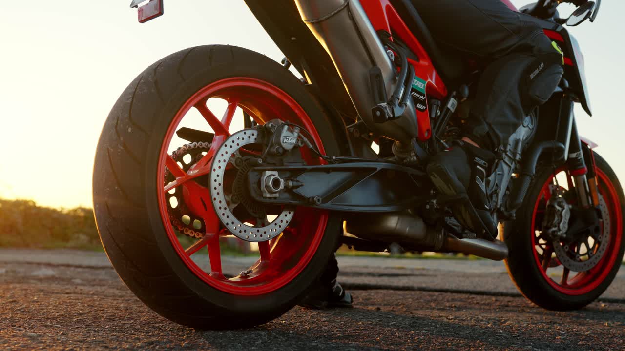 Motorcycle rear wheel close-up during sunset, with rider ready to hit the open road