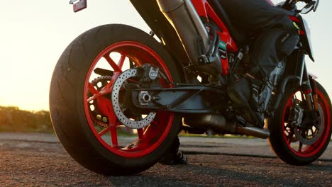 motorcycle rear wheel close-up during sunset, with rider ready to hit the open road