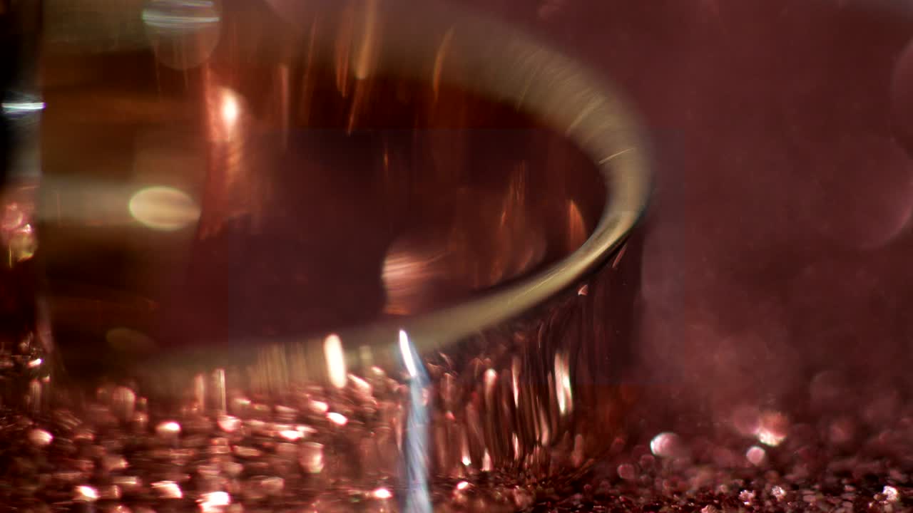 Fedi nuziali adagiate su una superficie lucida che brillano di luce, primo piano macro. Ruota in senso antiorario.