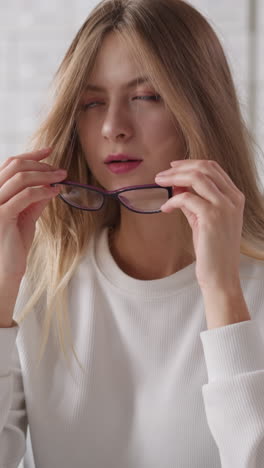 mujer se quita las gafas contra el caso de índice de tarjeta. dama rubia ajusta el cabello largo y suelto sentada en el escritorio en la biblioteca de la universidad. estudiante cansado de aprender