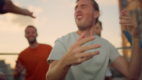 Happy-youth-dancing-at-nightclub.-Affective-man-raising-hands-at-disco-party.