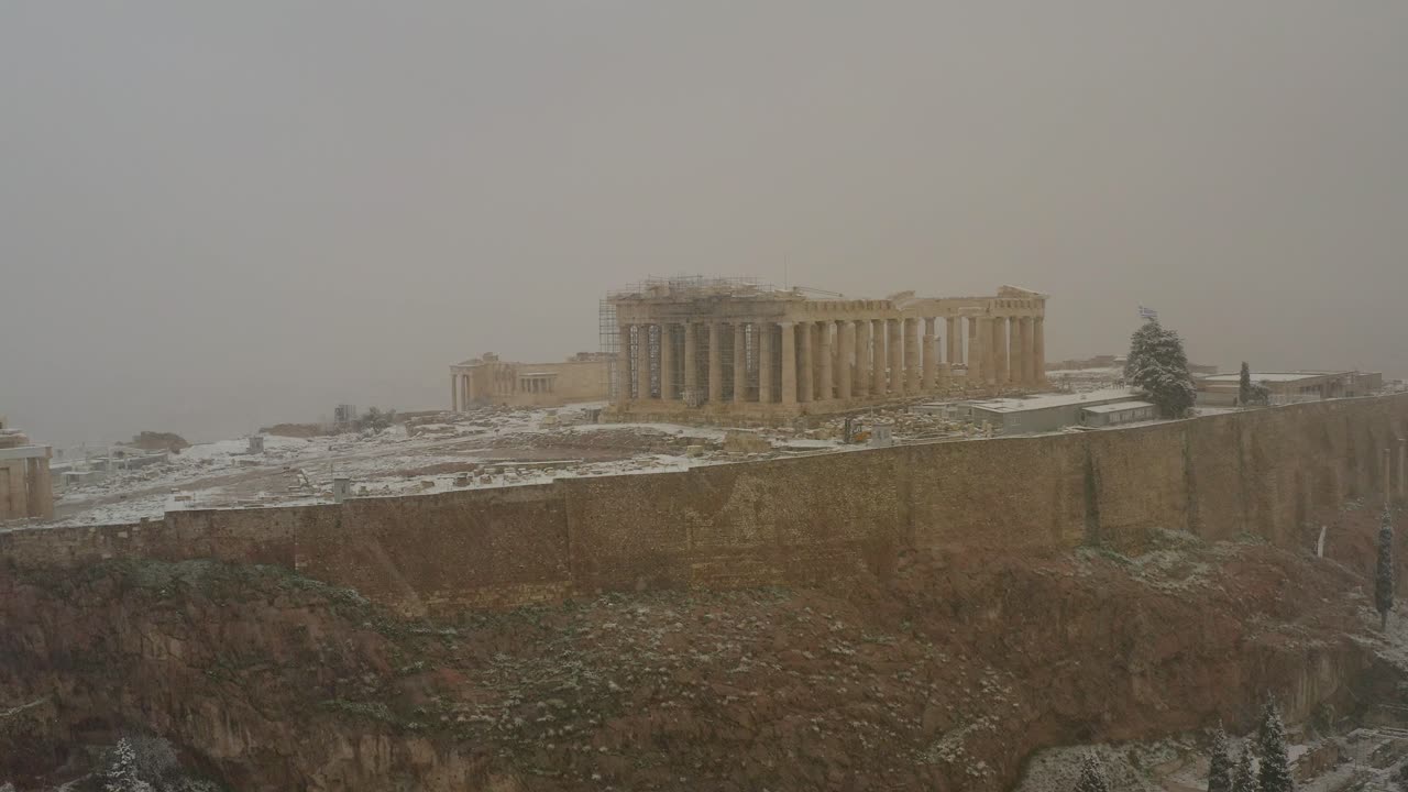 vista aérea alrededor del partenón en atenas, durante la ventisca - órbita, disparo de drones - calentamiento global que causa tormentas de nieve en lugares poco comunes