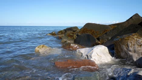 Klare-Blaue-Ozeanflut-Wäscht-Sich-Auf-Bunte-Steinkieselstrandküsteninsel-Urlaubsszene-Dolly-Nach-Links