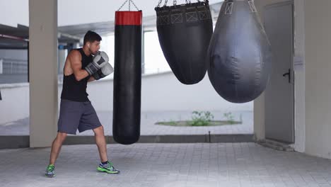 Volle-Länge-Eines-Boxers,-Der-Auf-Einem-Boxsack-Im-Parkzonen-Fitnessstudio-Trainiert